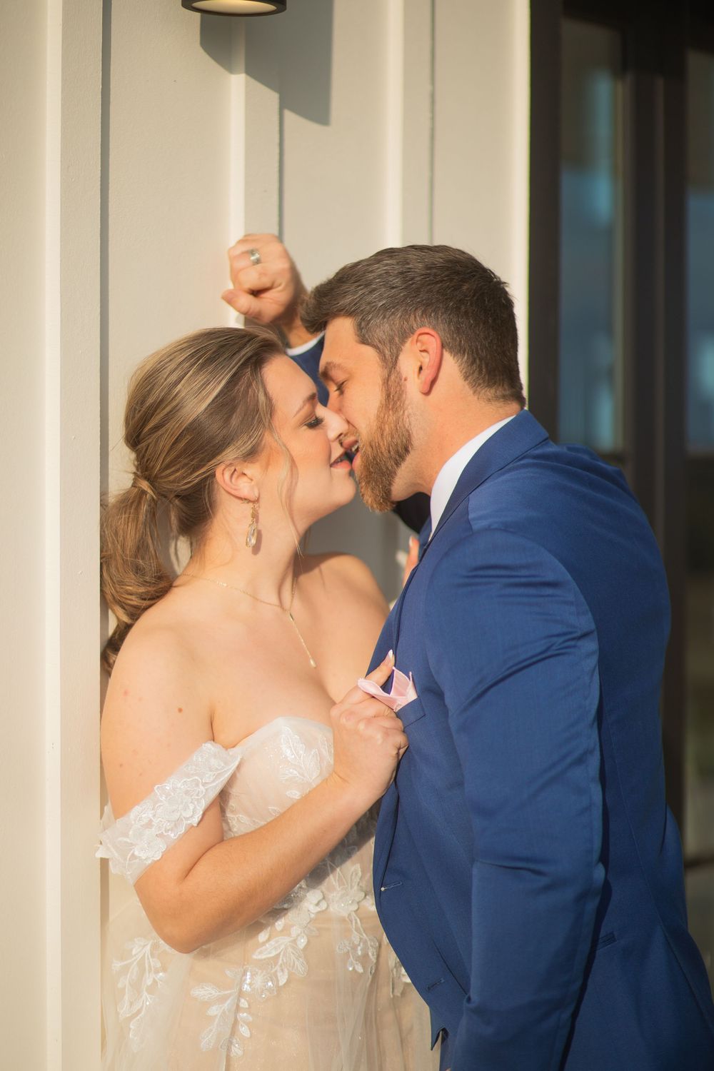 A bride and groom share intimate kisses with different expressions against a neutral wall.