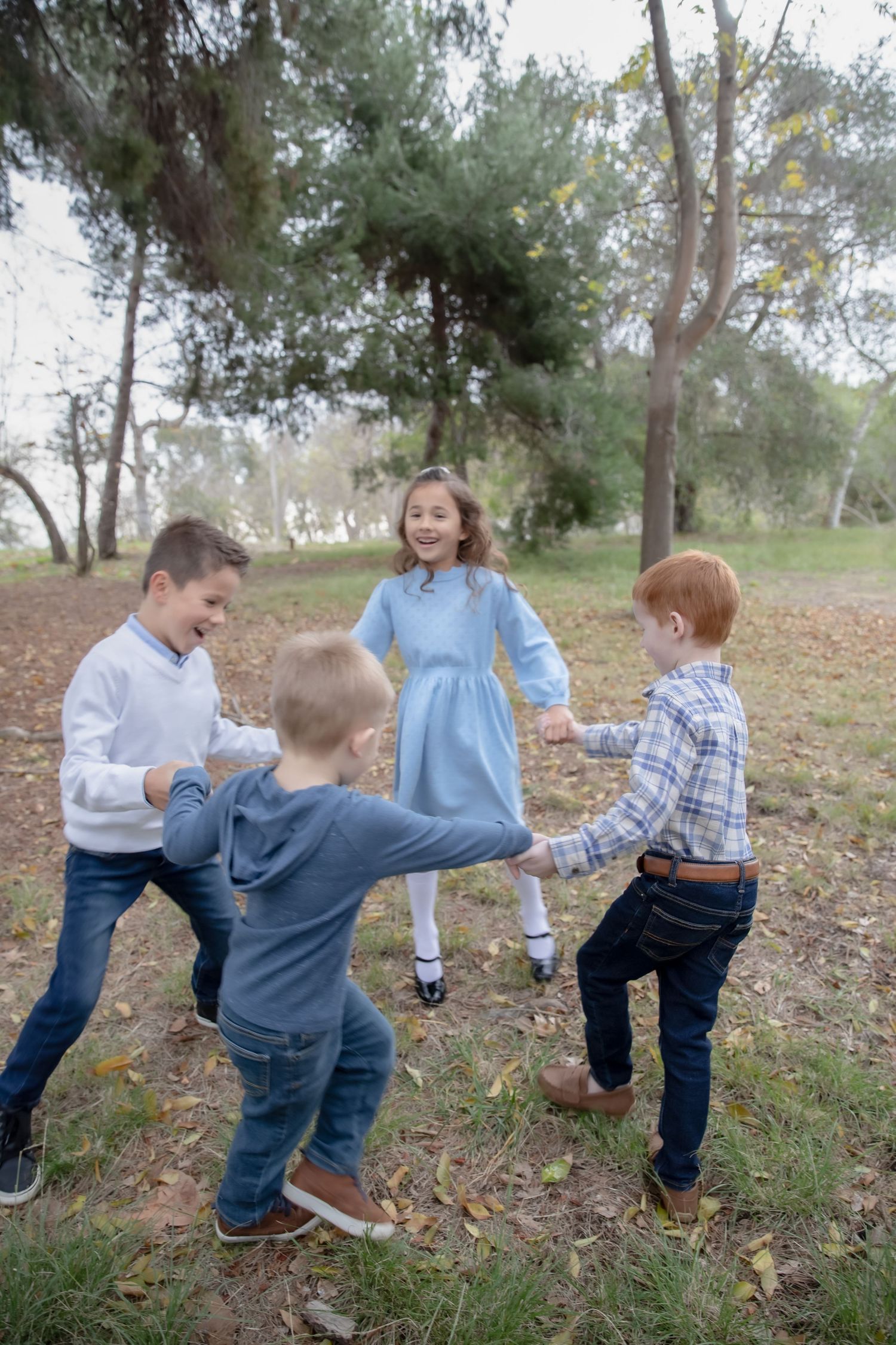 Children playing and running together through a wooded area on an autumn day.