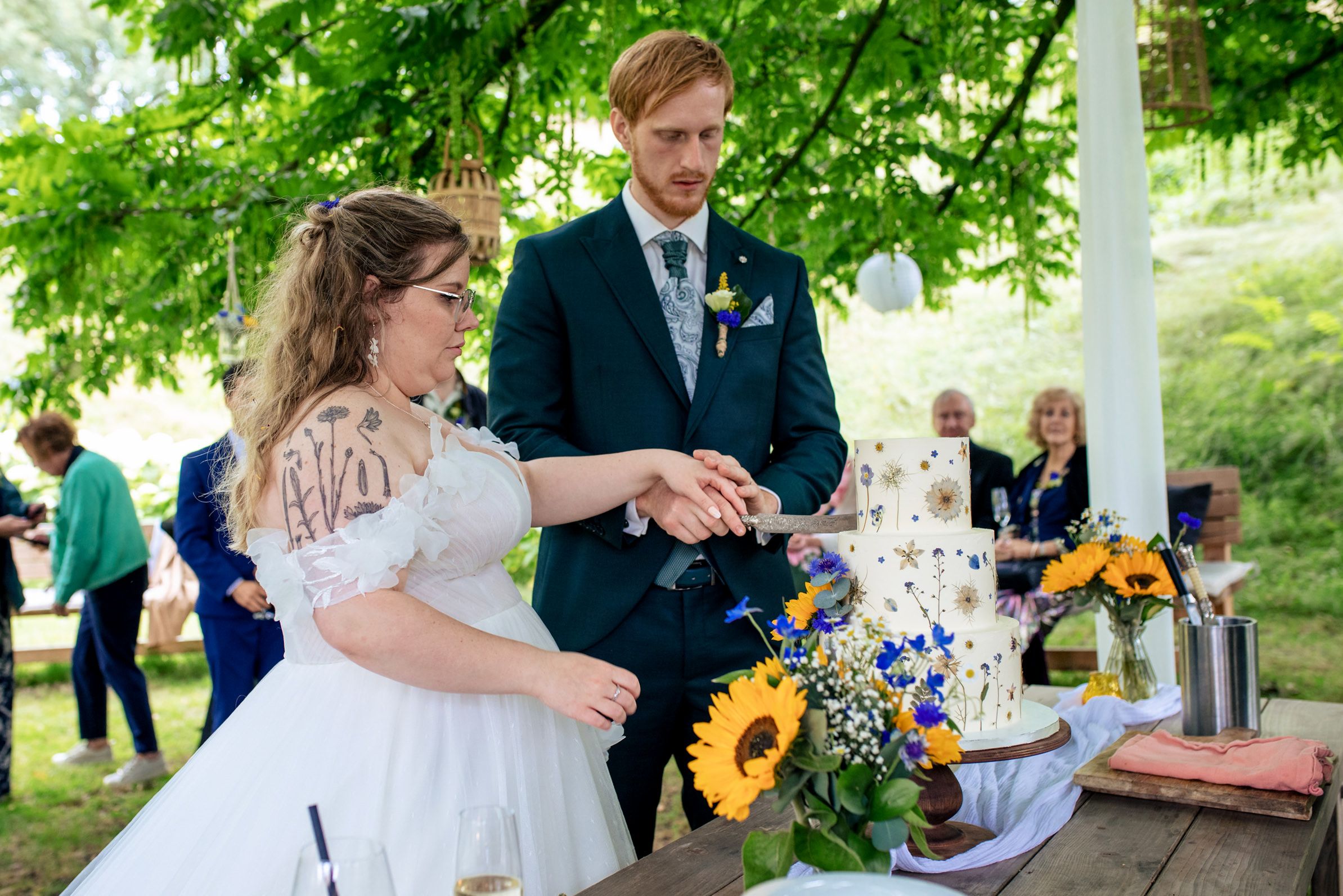 Bruidspaar snijdt een bruidstaart met eetbare bloemen aan tijdens hun trouwdag bij Fier in Bussum