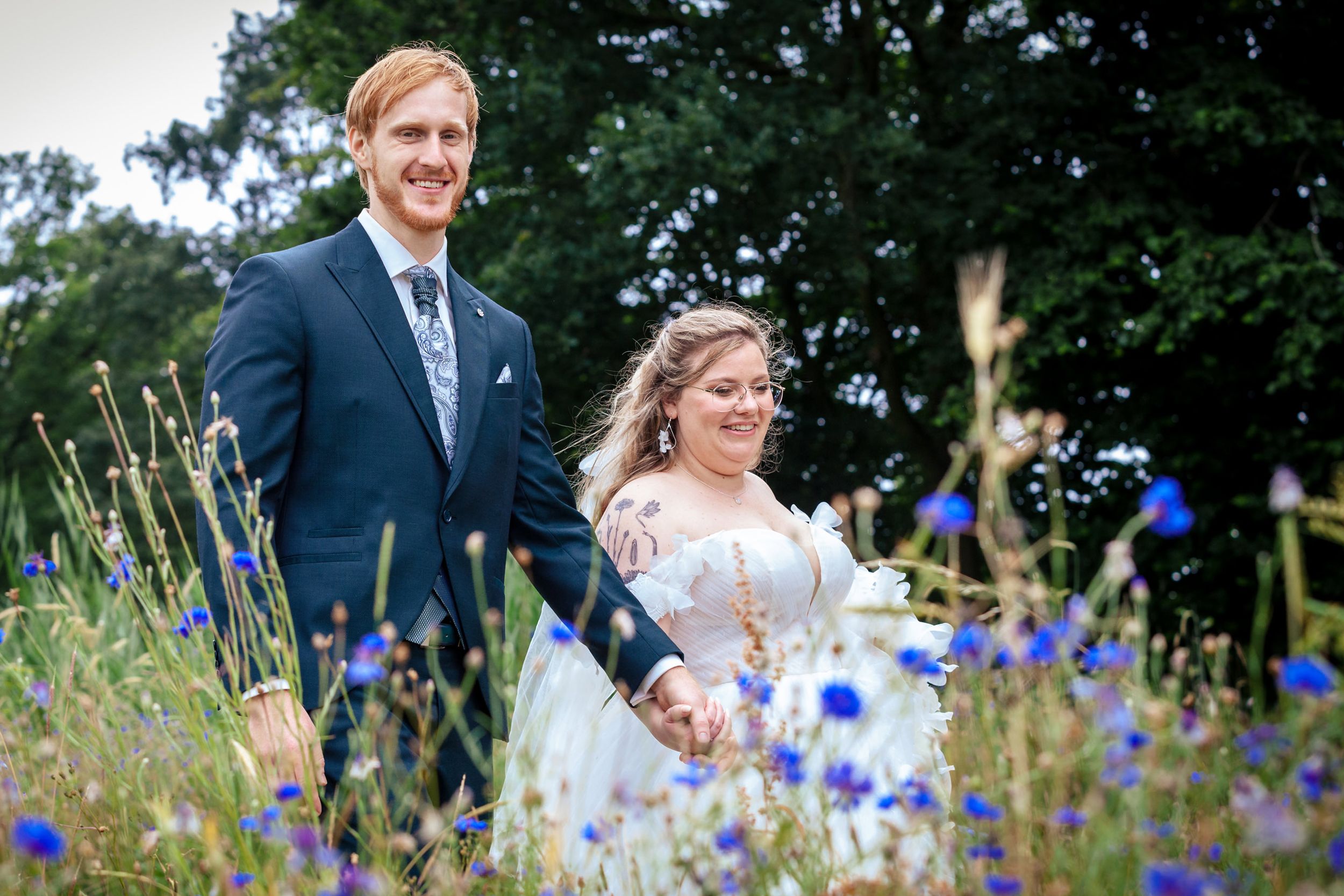 Bruidspaar wandelt door de Botanische Tuinen in Utrecht met wilde bloemen op de voorgrond