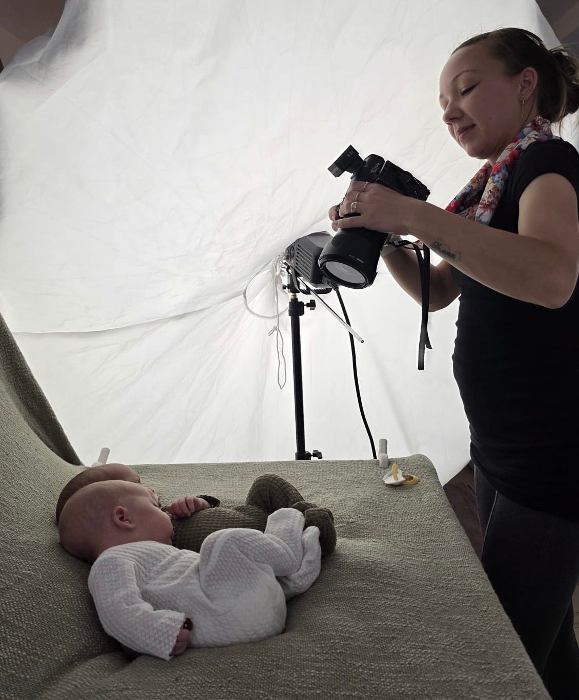Photographer taking pictures of newborn on white backdrop in professional studio setting.