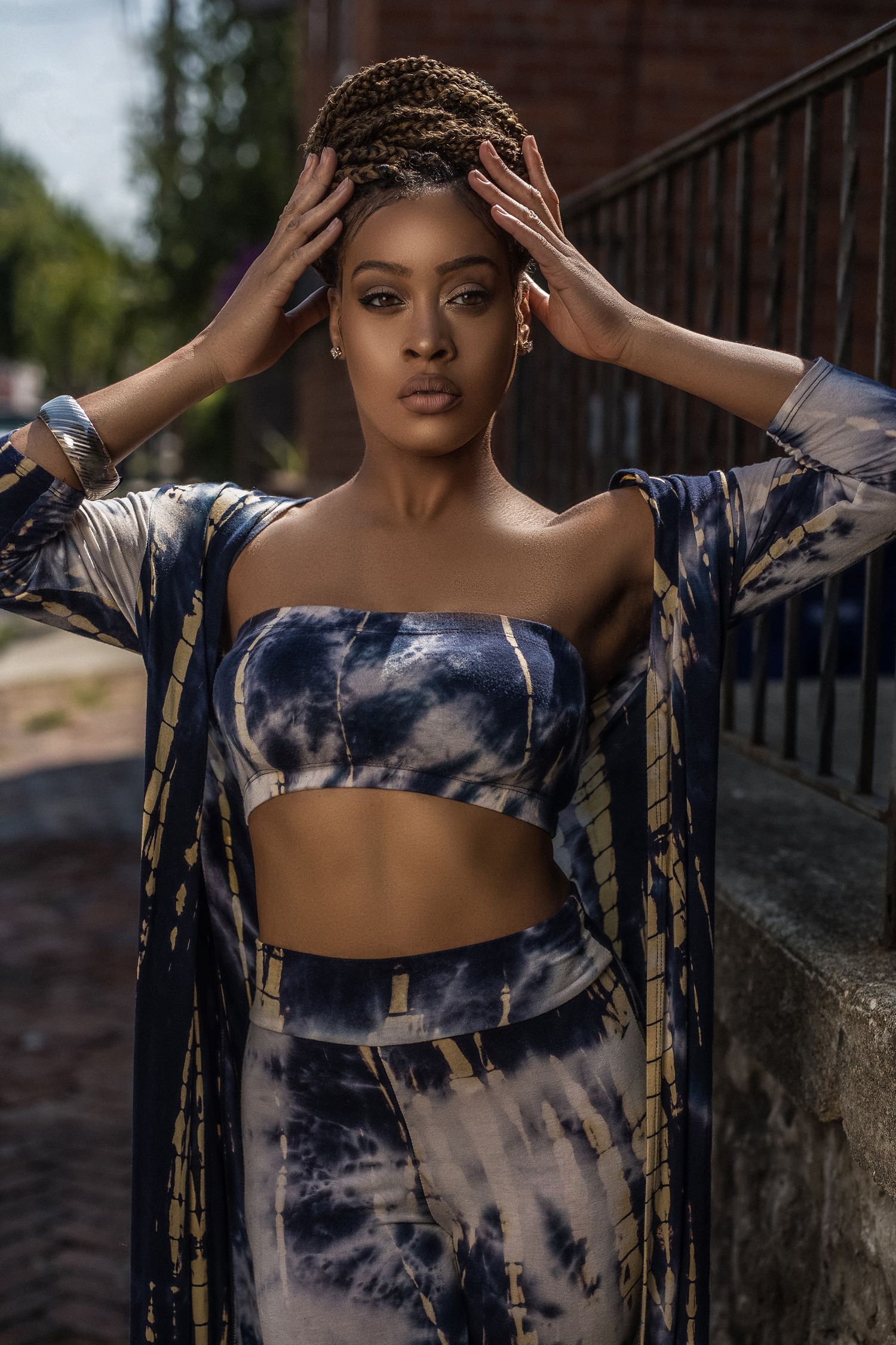 A fashion photoshoot series featuring a model in a navy blue and white tie-dye outfit against an urban backdrop.