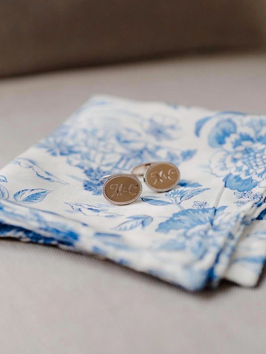 Blue and white embroidered fabric shown in detail with silver coin placed on its delicate floral pattern.