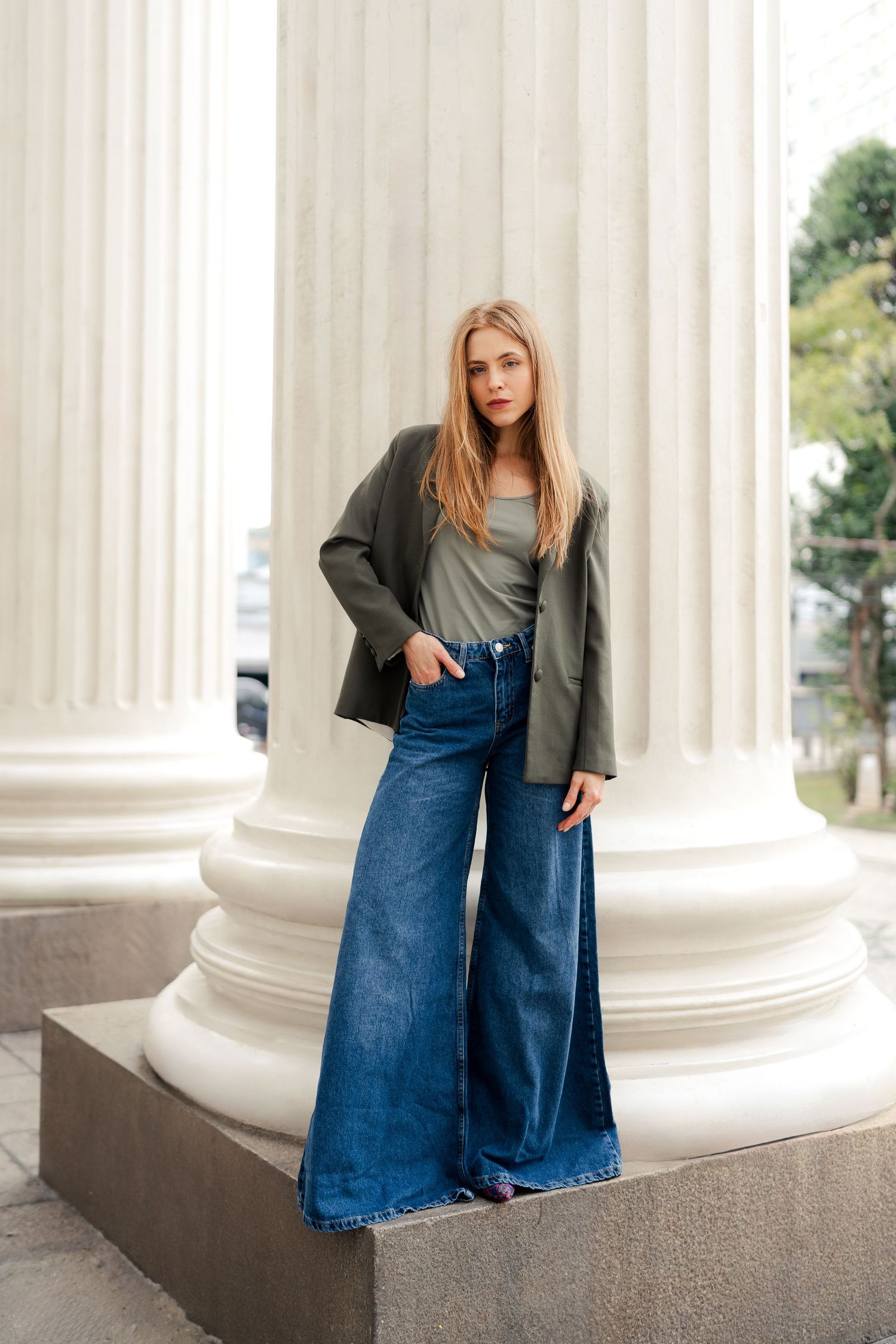 Modern fashion series featuring denim and gray coat against architectural white columns.