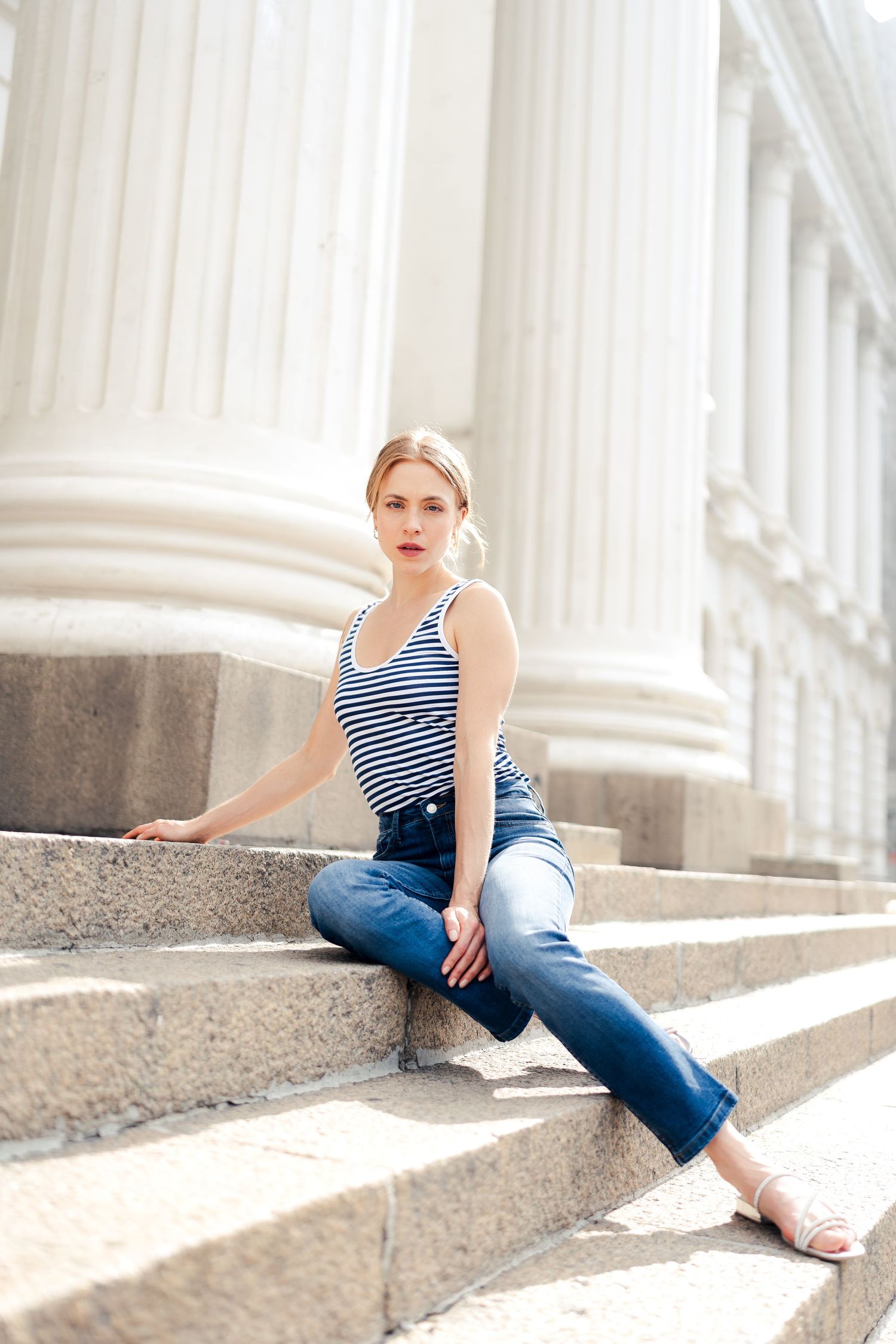 Fashion portrait series showing casual summer style with striped top and jeans on classic columned steps.