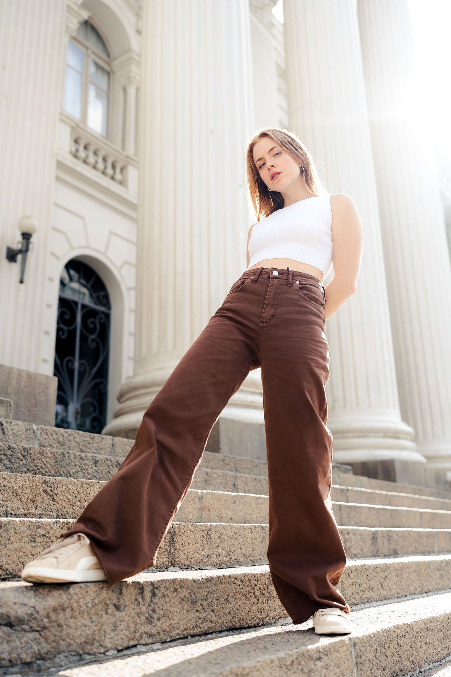 Artistic photo series showcasing brown pants and white top against elegant white columns.
