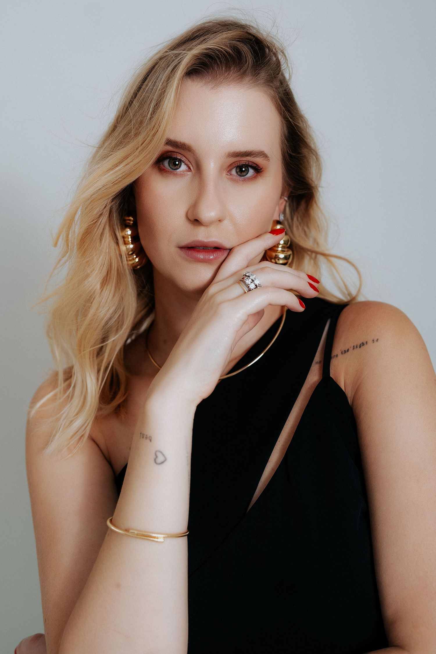 Fashion portrait series showing jewelry details and black top against light background.