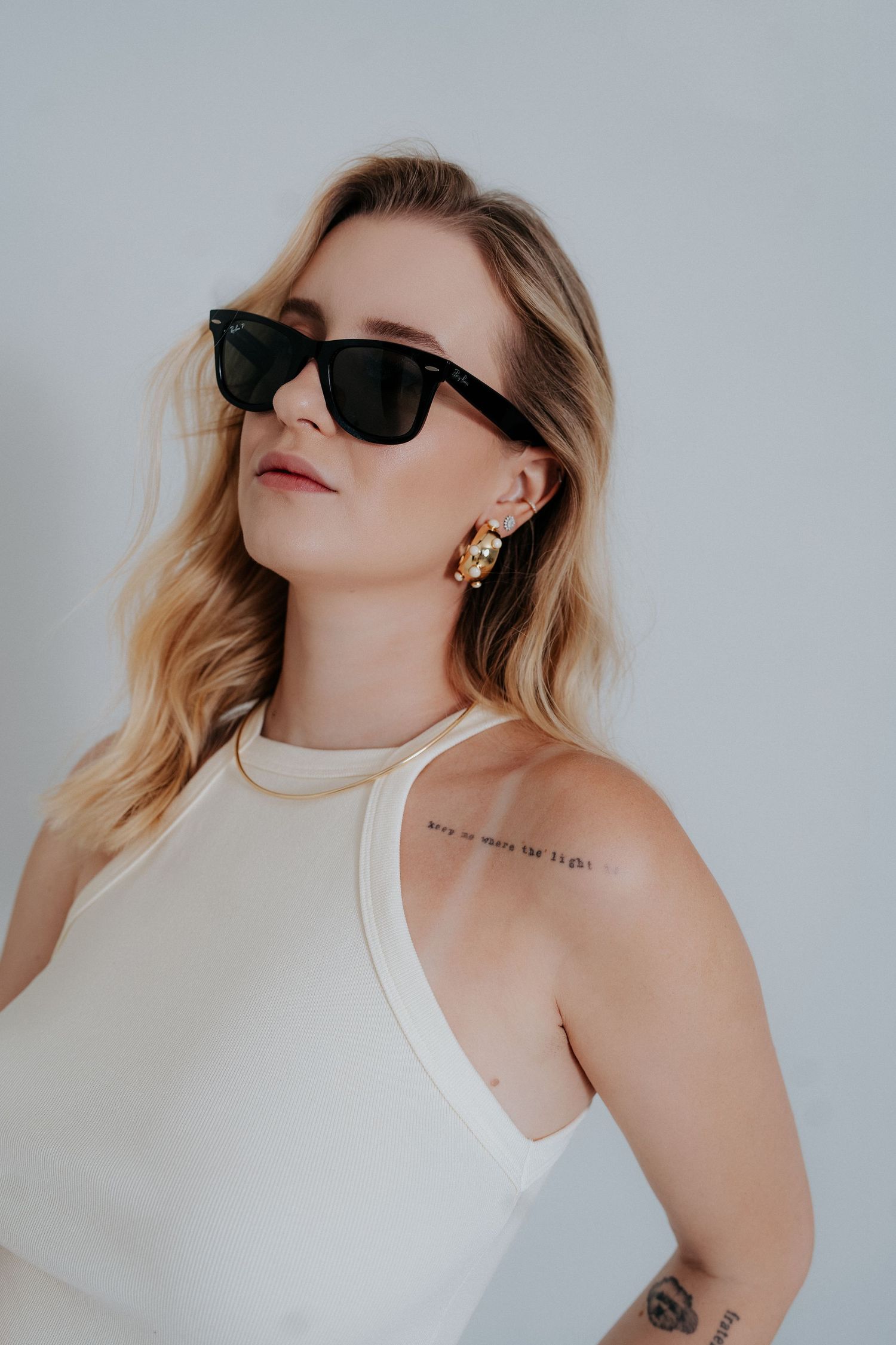 A series of minimalist fashion portraits showing someone in a white tank top and sunglasses against a light background.