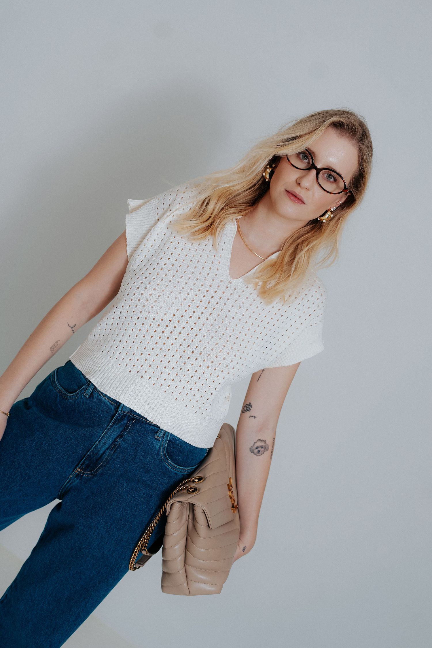 A person wearing a white eyelet top and blue jeans poses in a series of casual fashion shots against a light background.