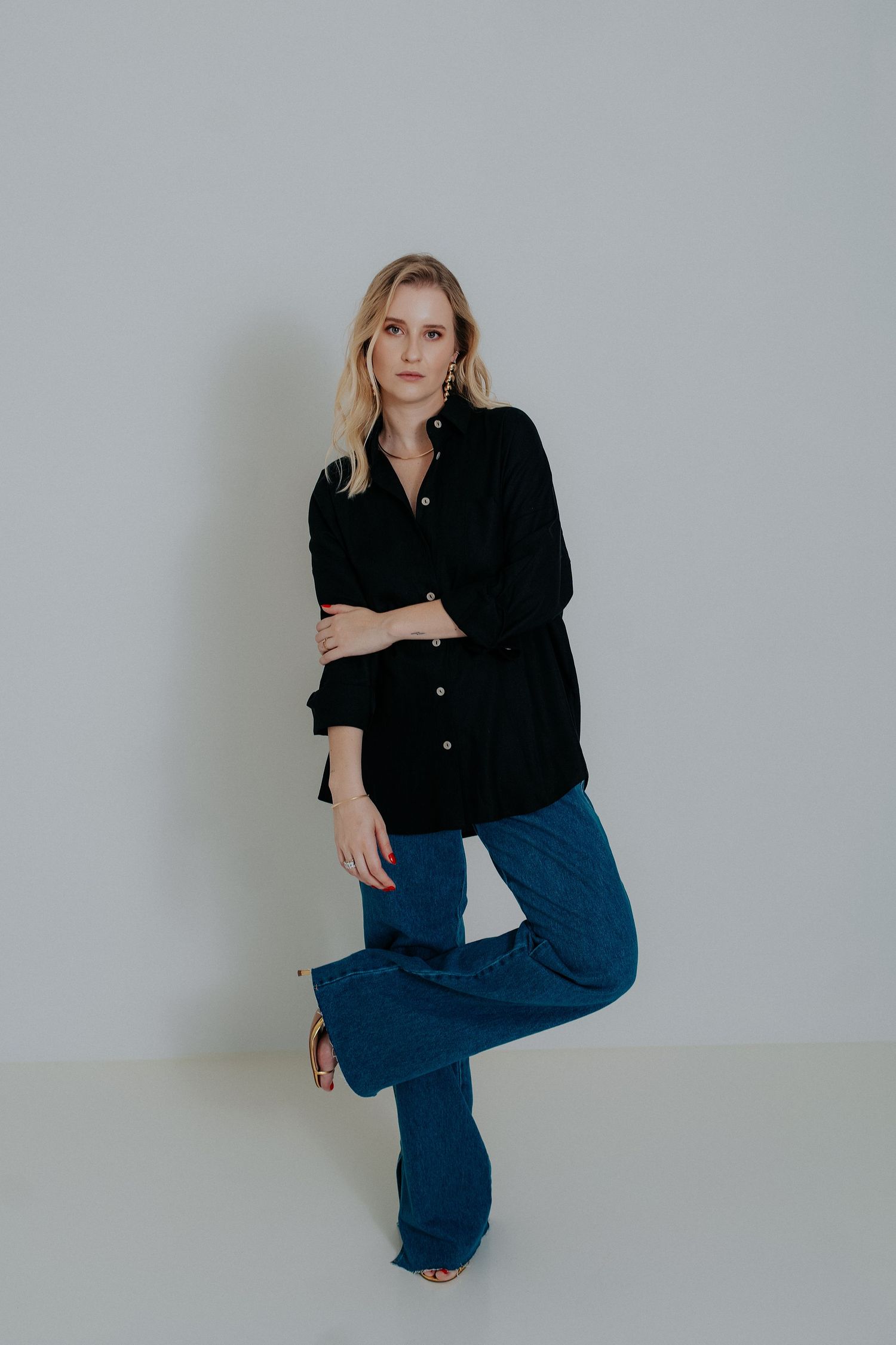 Fashion model in black button-down shirt and blue wide-leg pants poses against white backdrop in four artistic shots.