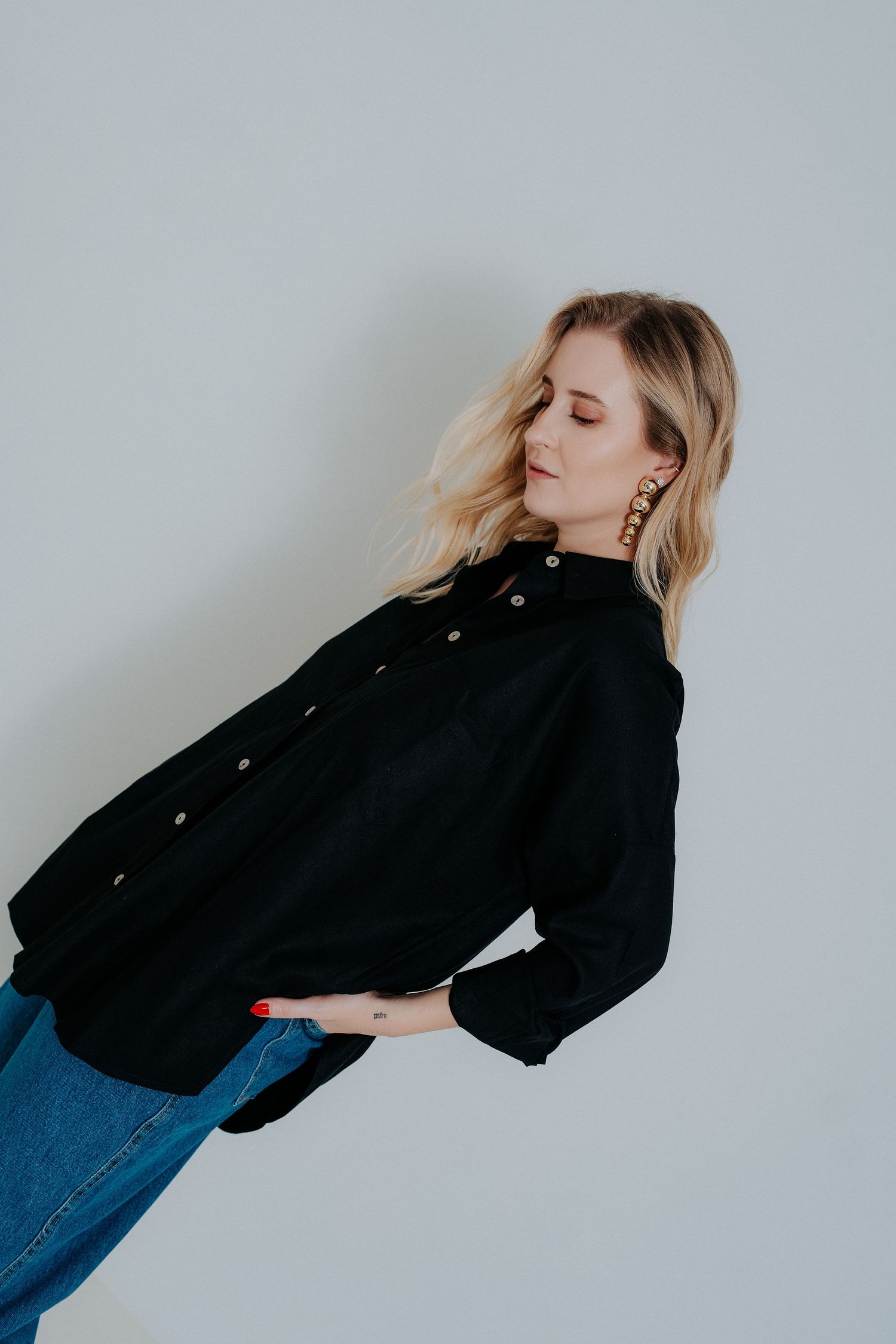 A series of fashion photos showing a model in a black jacket and jeans posing against a white wall in dynamic poses.