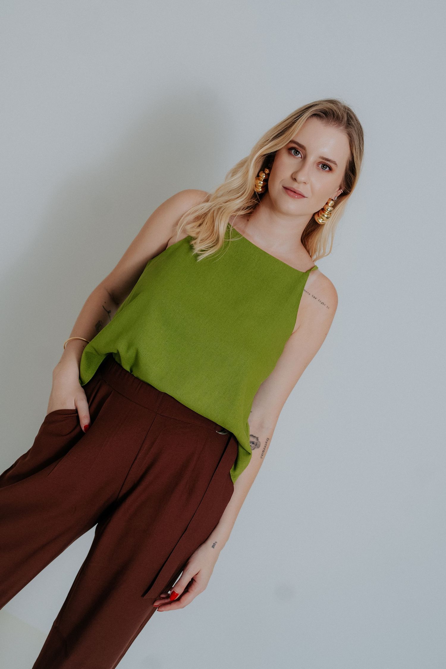 A two-toned sleeveless dress in olive green and chocolate brown colors against a light gray background.
