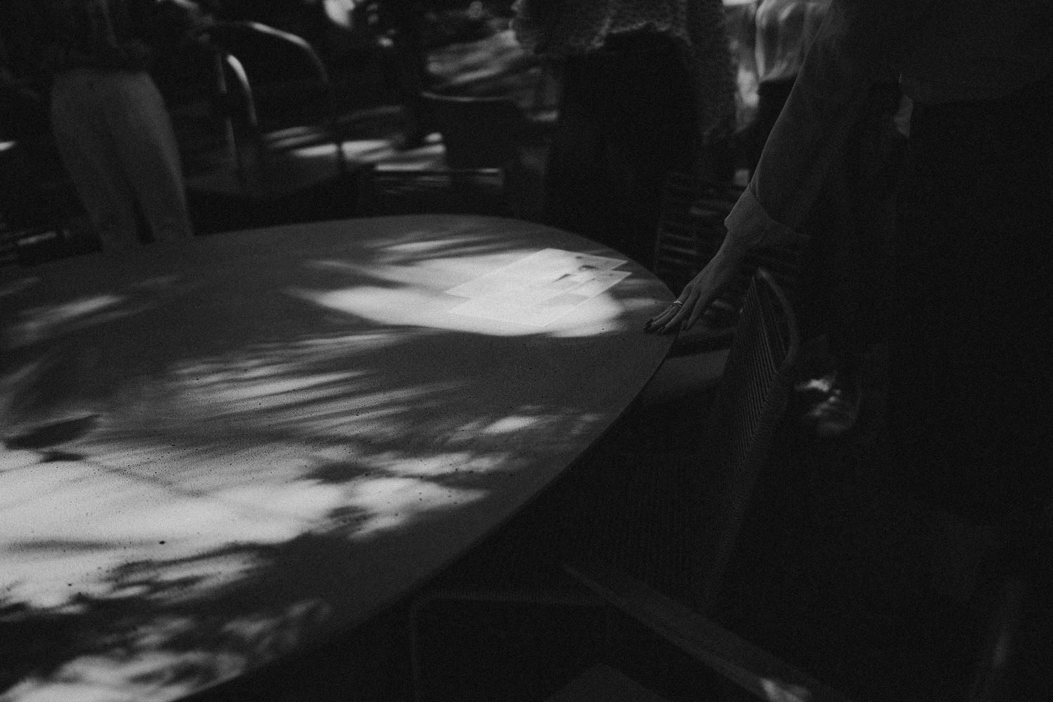 Artistic black and white photograph showing dappled sunlight and shadows on outdoor furniture.