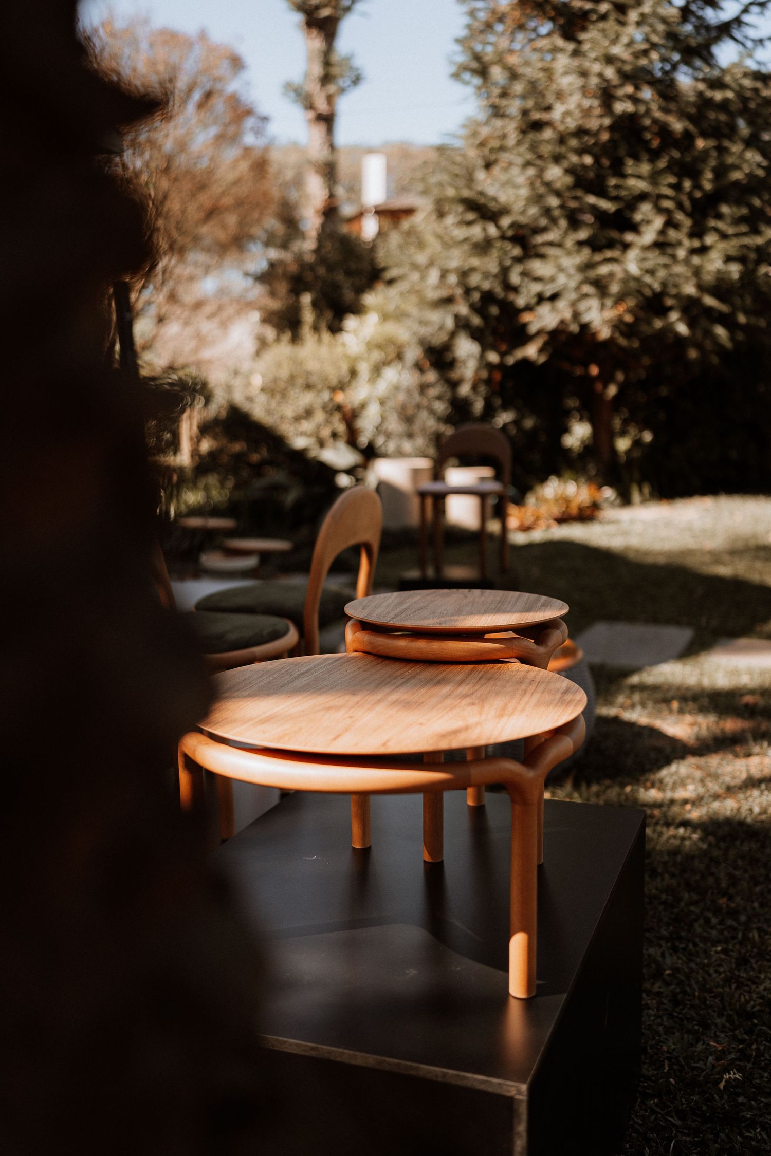 A series of artistic shots showing a wooden round table in dappled sunlight against a dark background.