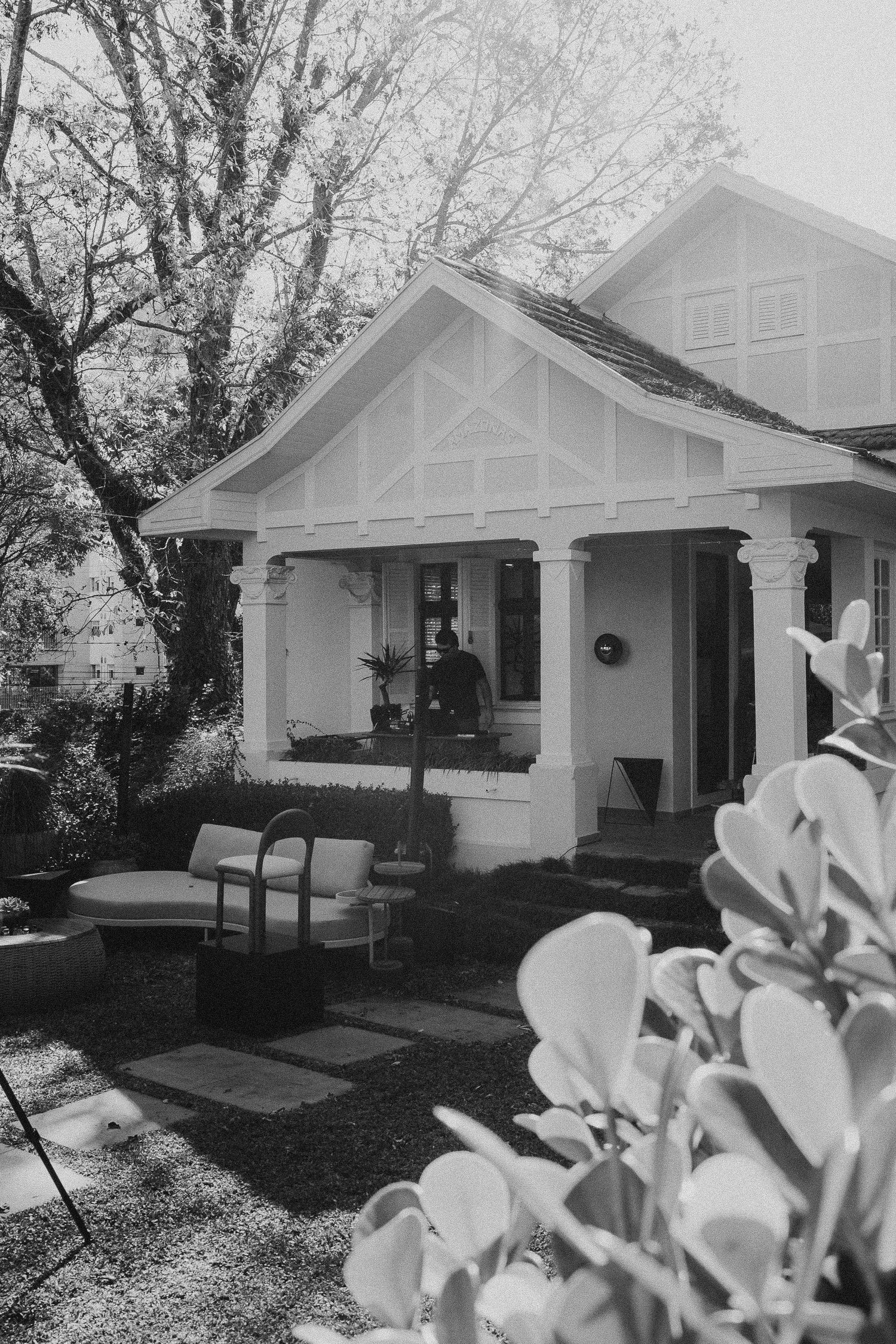 A sequence of black and white photos showing a craftsman bungalow style house with white exterior and dark trim.