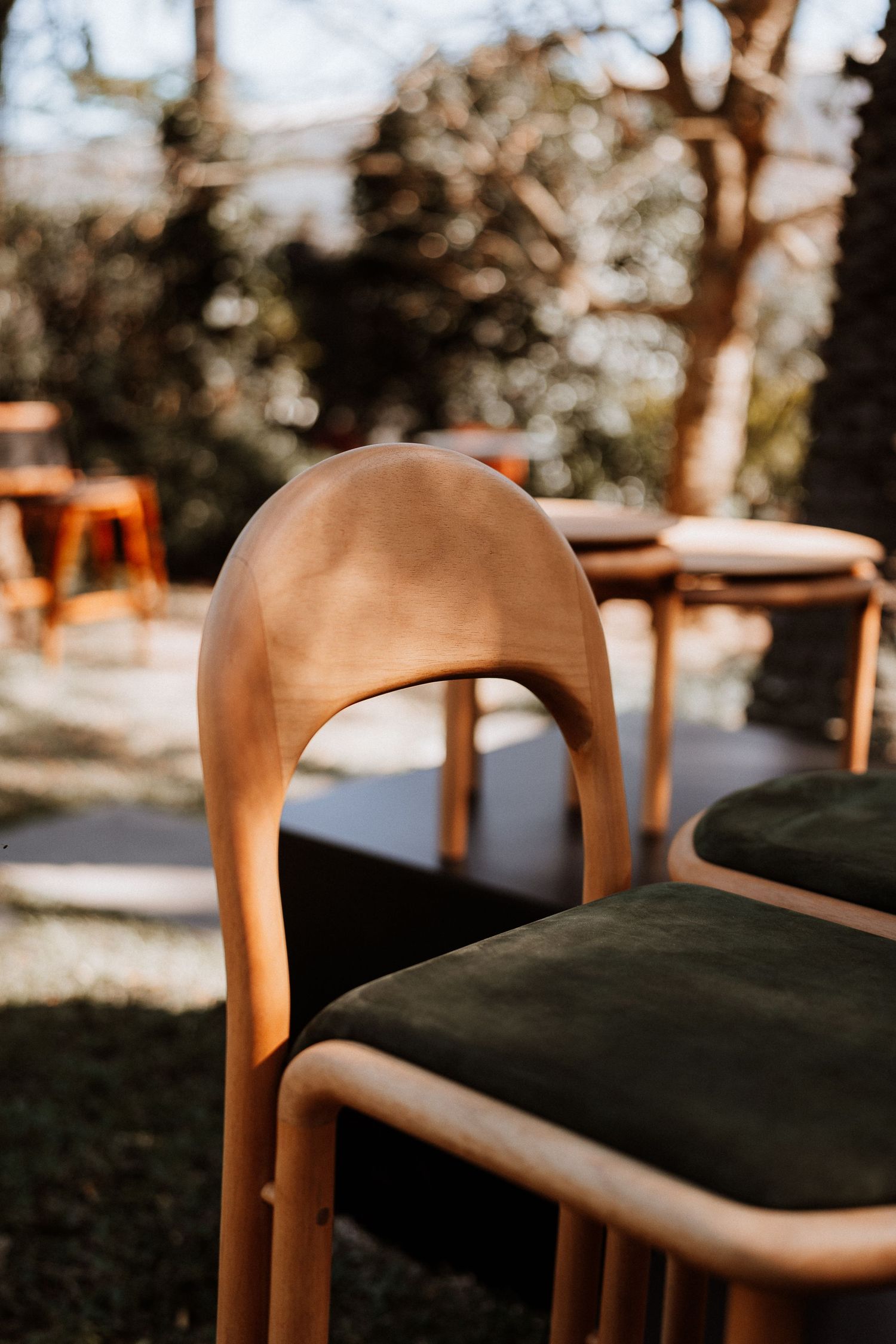 Modern wooden chair with black upholstered seat cushion shown in natural outdoor lighting.