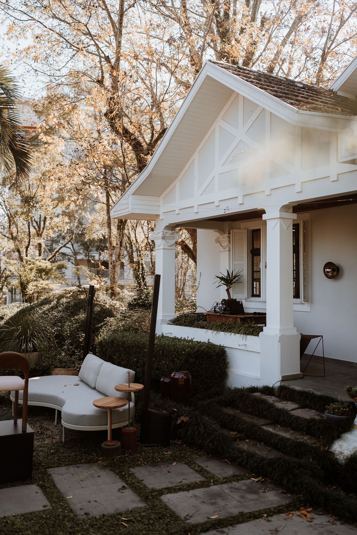 White craftsman bungalow with a covered porch and columns surrounded by autumn trees.