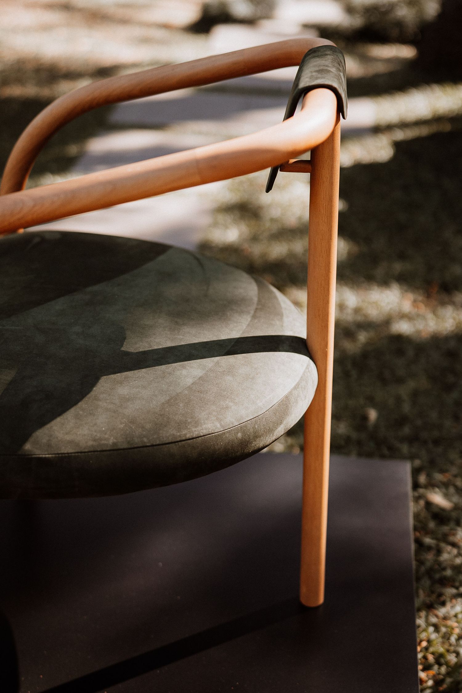 Close-up detail of a modern chair armrest showing wood grain and curved design elements.