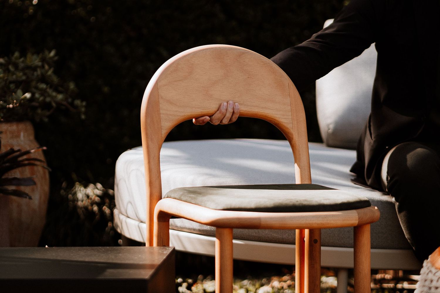 Curved wooden chairs with white cushions arranged in a row at an outdoor event venue.