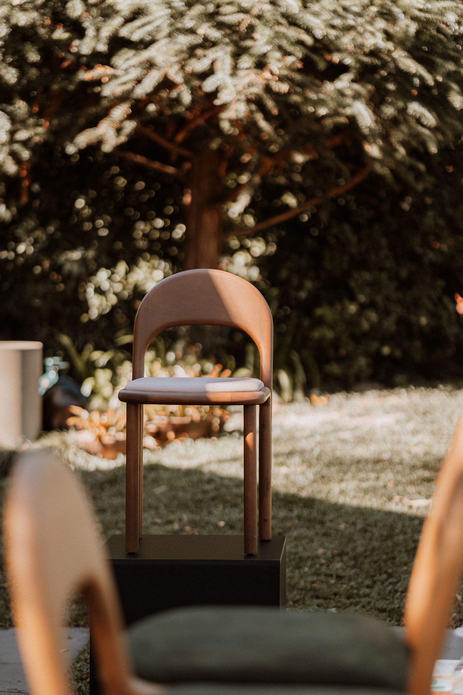 Minimalist wooden furniture silhouetted against a bright, bokeh-filled natural backdrop.