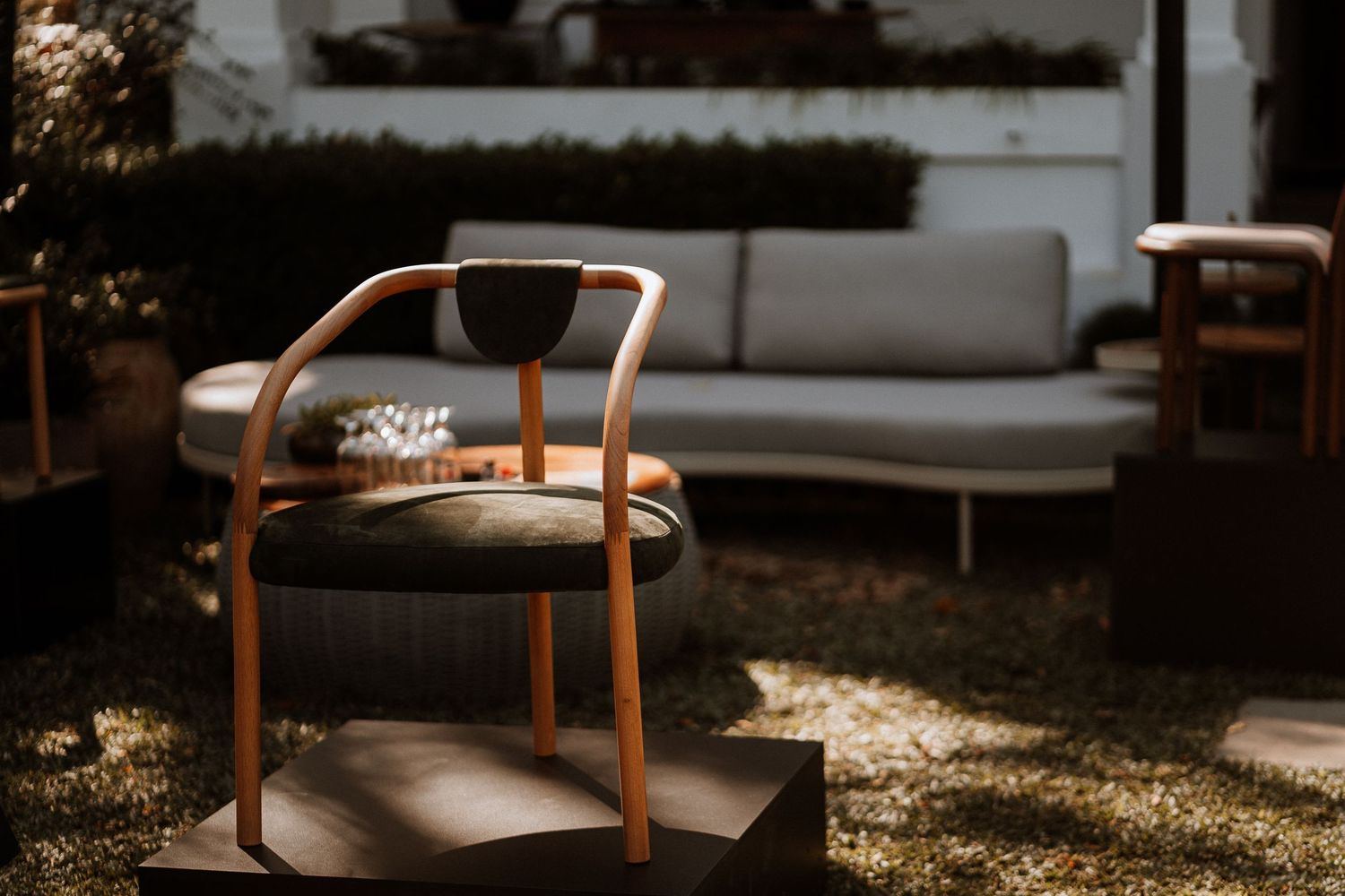 Wooden chairs with curved backs and dark cushions arranged in an outdoor seating area.