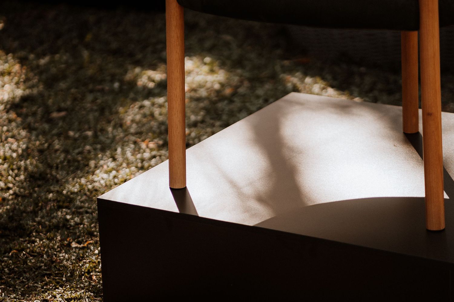 Sunlight illuminates wooden chair seats and backs creating a minimalist composition with strong shadows.
