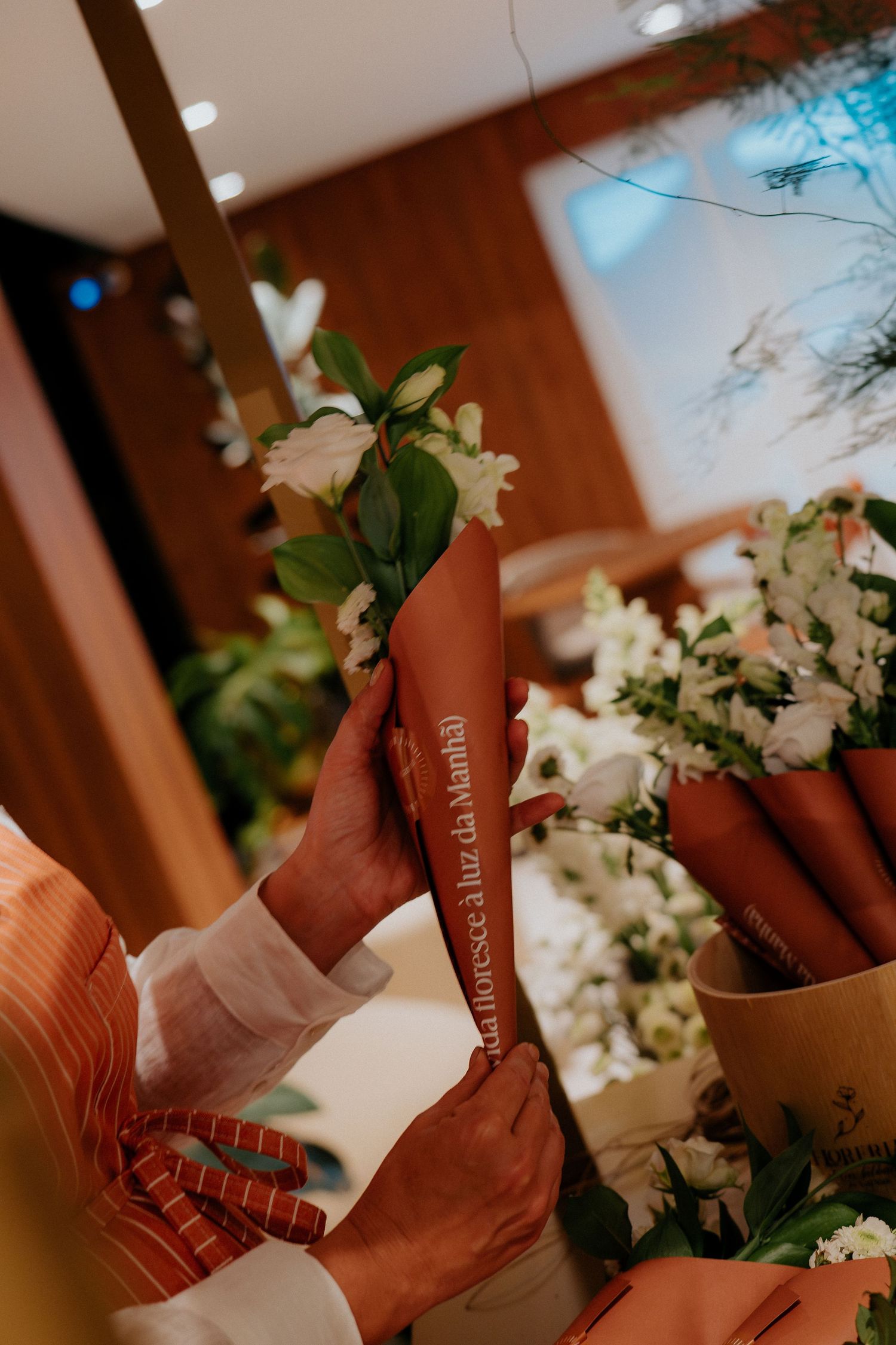 A brown leather Bible or book rests among delicate white floral arrangements in an indoor setting.
