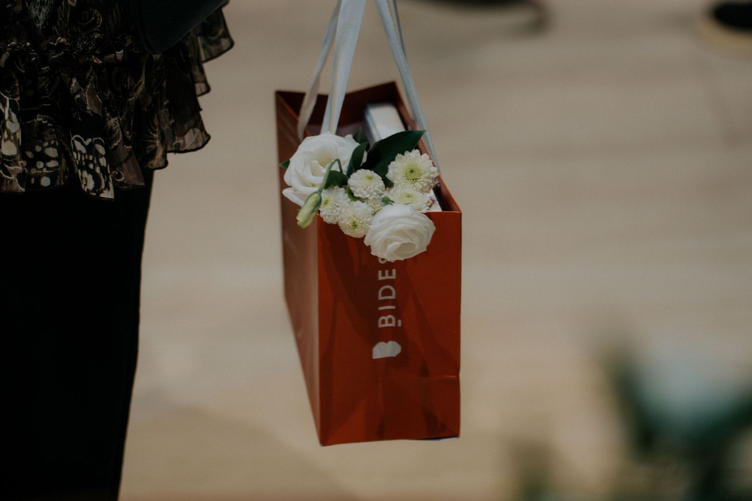 Leather-bound books displayed alongside elegant white flowers and greenery in soft lighting.