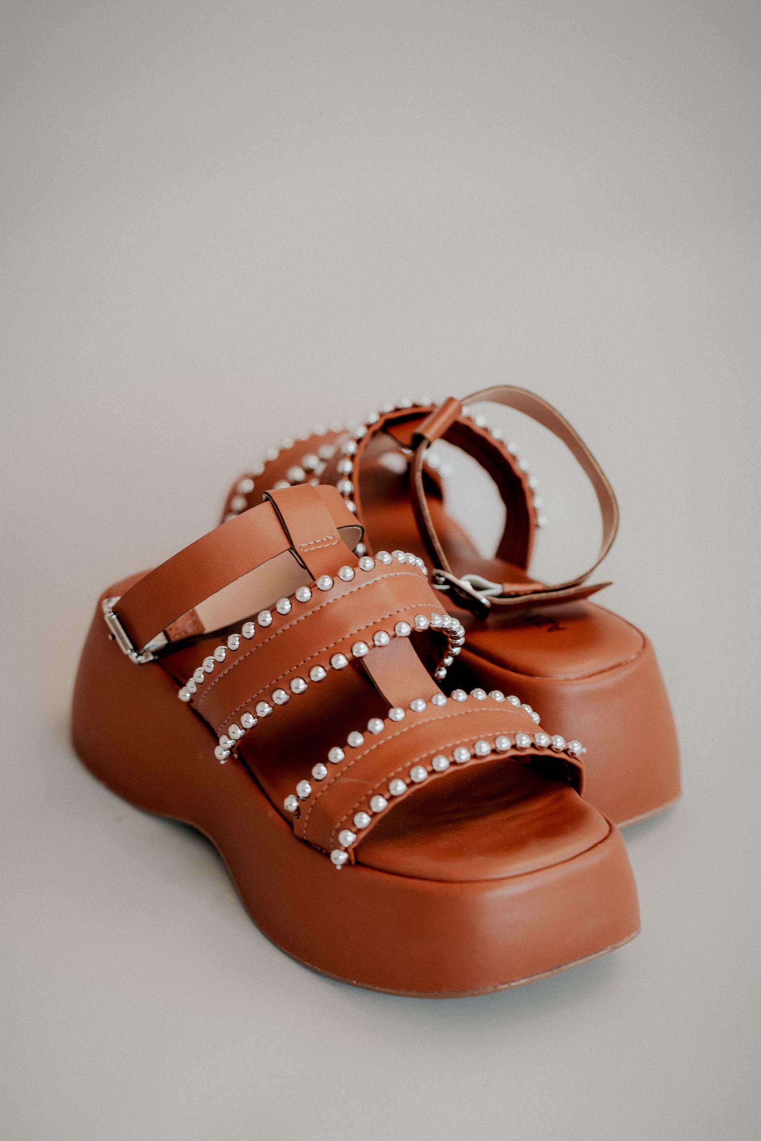 Brown leather sandals with crystal embellishments and buckle straps photographed from different angles on white background.