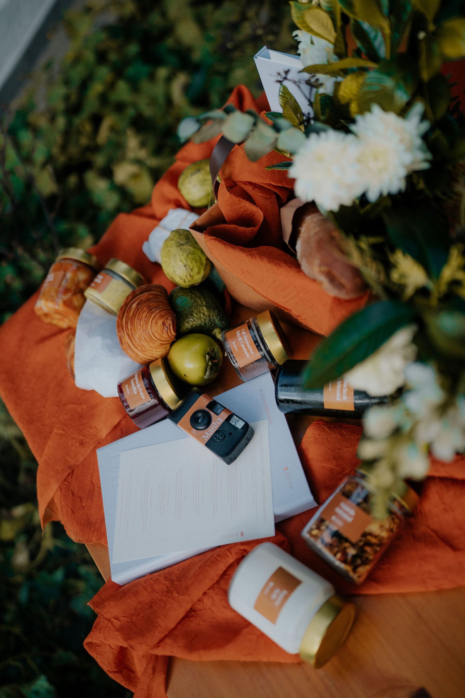 White documents and glass jars scattered on an orange textile surface with natural lighting.