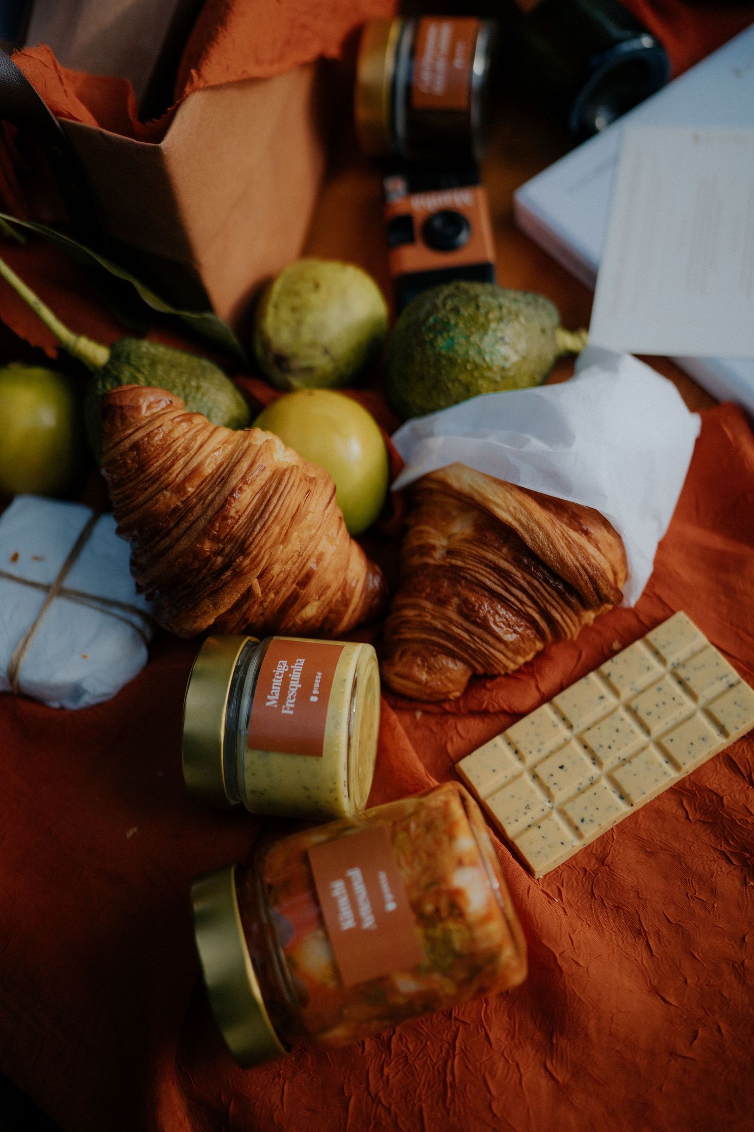 White chocolate bars and croissants displayed with jars on a terracotta colored surface.