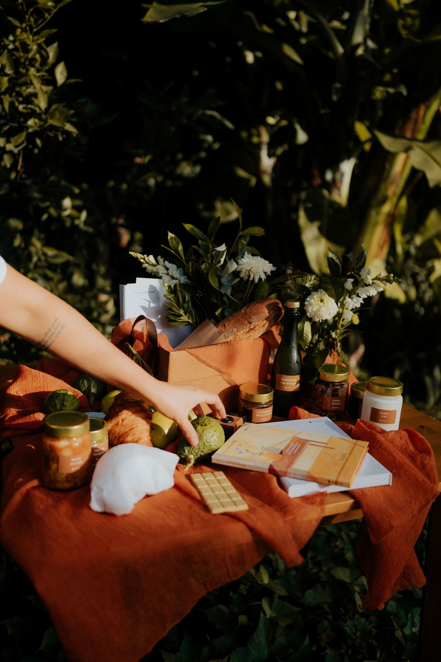 A cozy outdoor setup with papers and food items arranged on a rust-colored cloth.