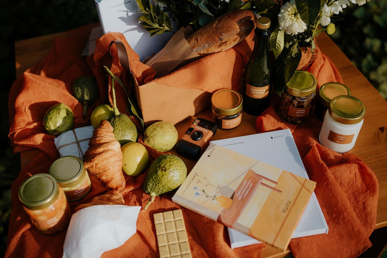Various items including papers and jars arranged on an orange textile in natural light.