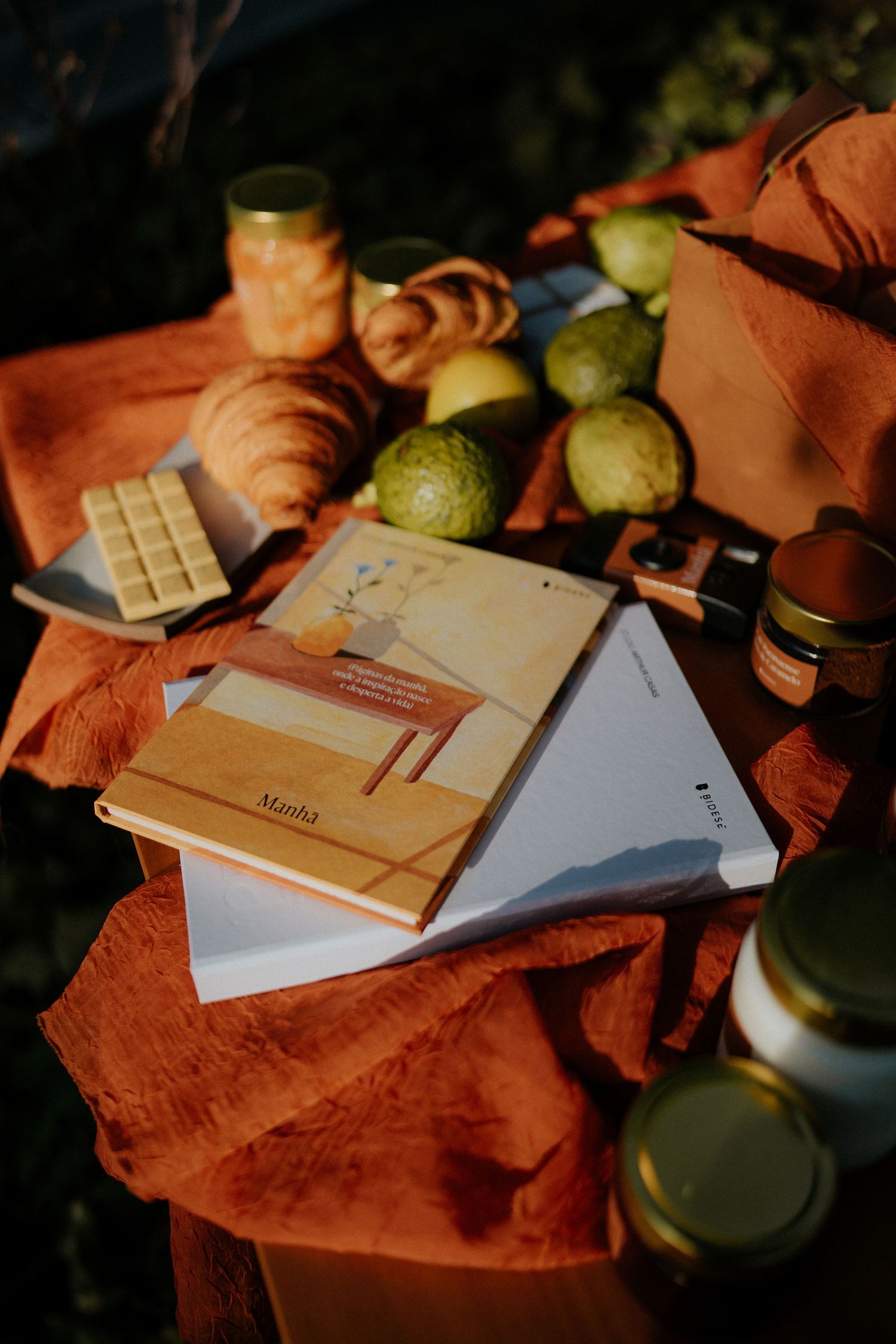 Documents and glass containers arranged on an orange cloth in atmospheric lighting.