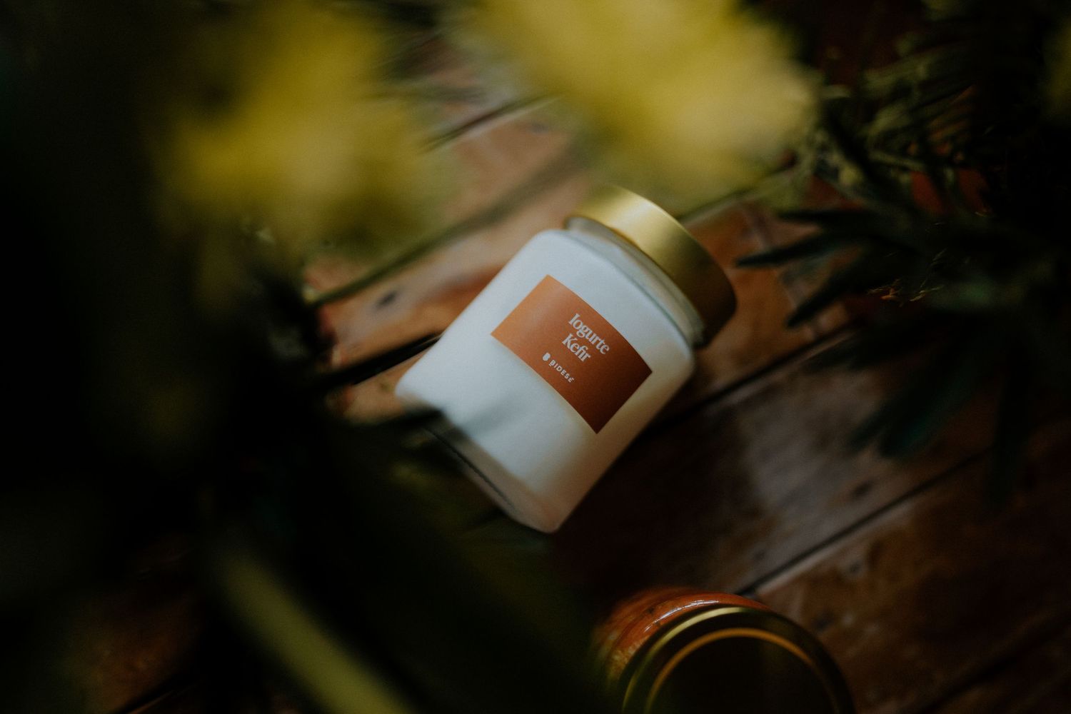 White cosmetic jar photographed in moody lighting with blurred yellow flowers.