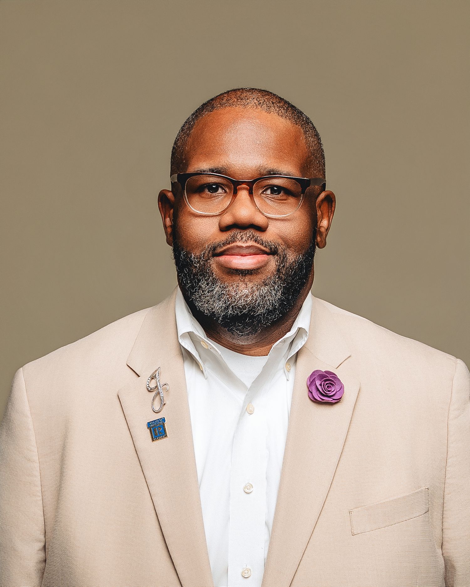 Professional headshot series showing person in beige suit and glasses with a neat beard against neutral background.