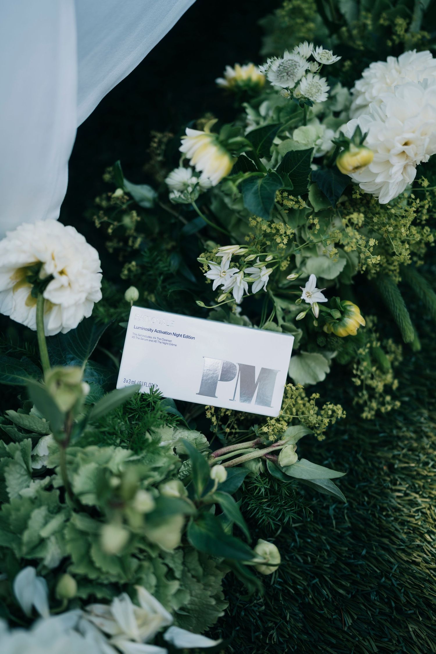 A business card nestled among white flowers and greenery in an elegant garden arrangement.