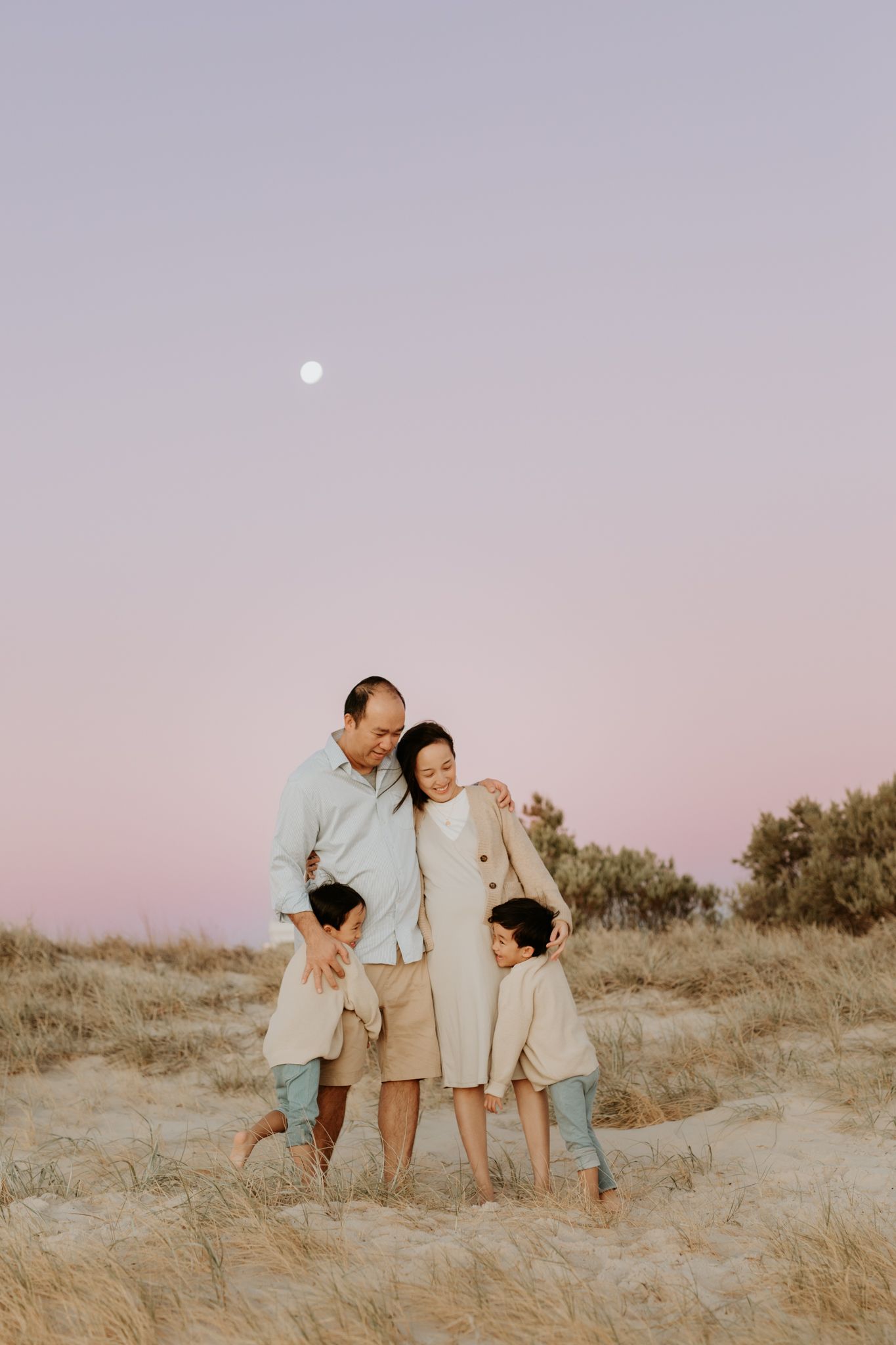 Parents and children snuggle on a sandy Adelaide beach at blue hour under the moon during a family photography session with Lauren Lunn.