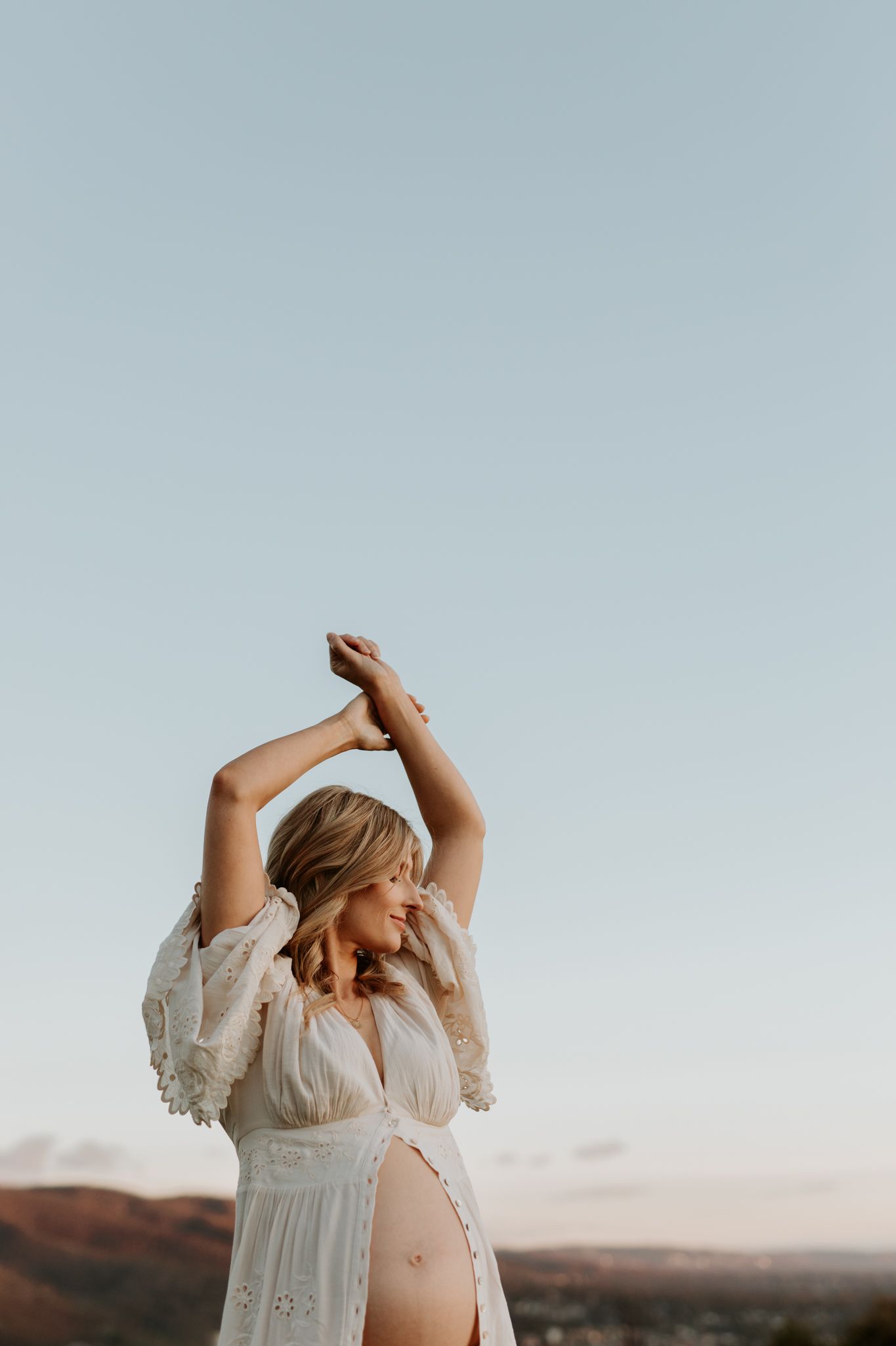 Lauren Lunn Photography captures a serene maternity moment: mother-to-be in gown, bump highlighted, under a sunny, golden sky.
