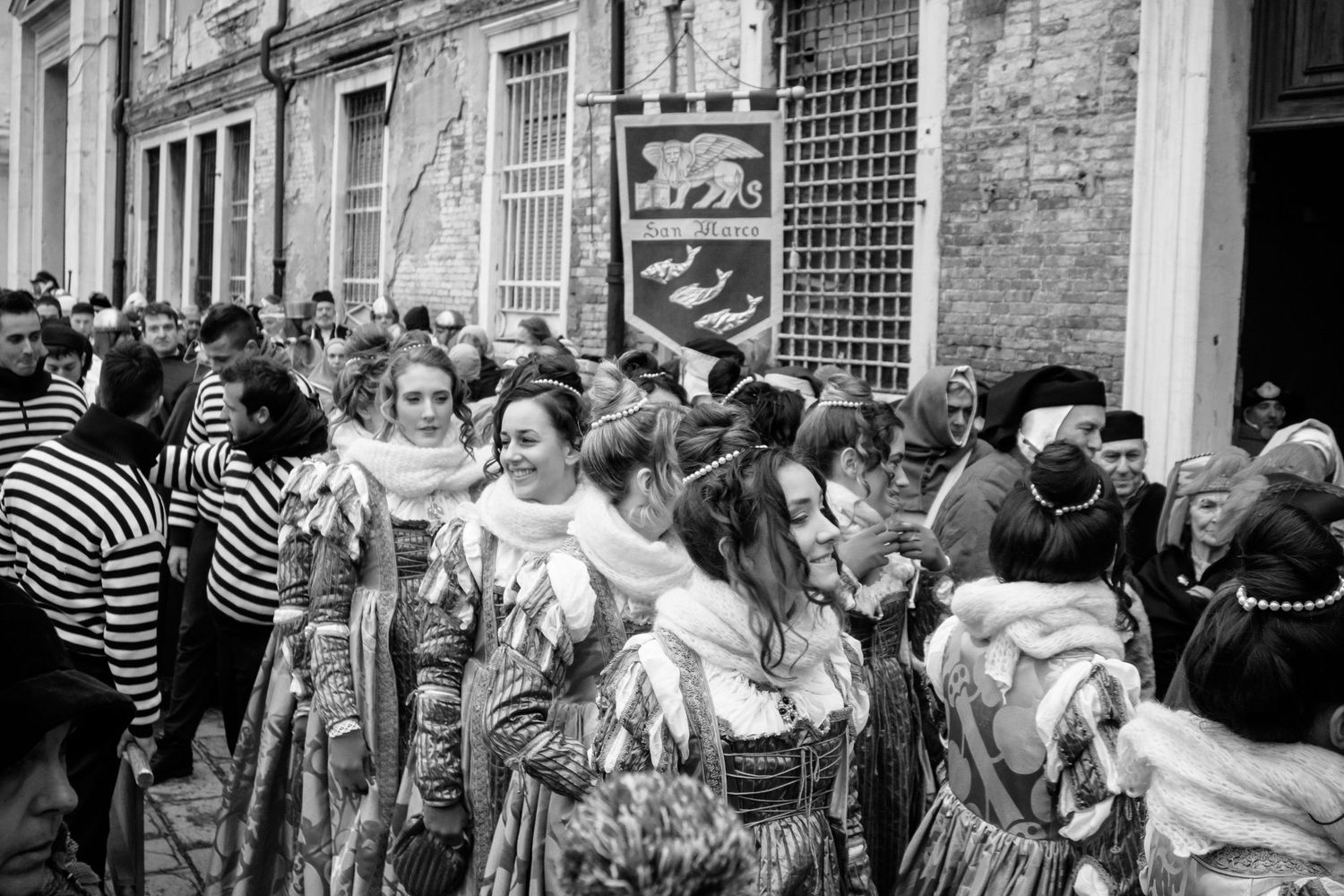 A black and white collage showing a group of people waiting in line outside during an urban event or gathering.