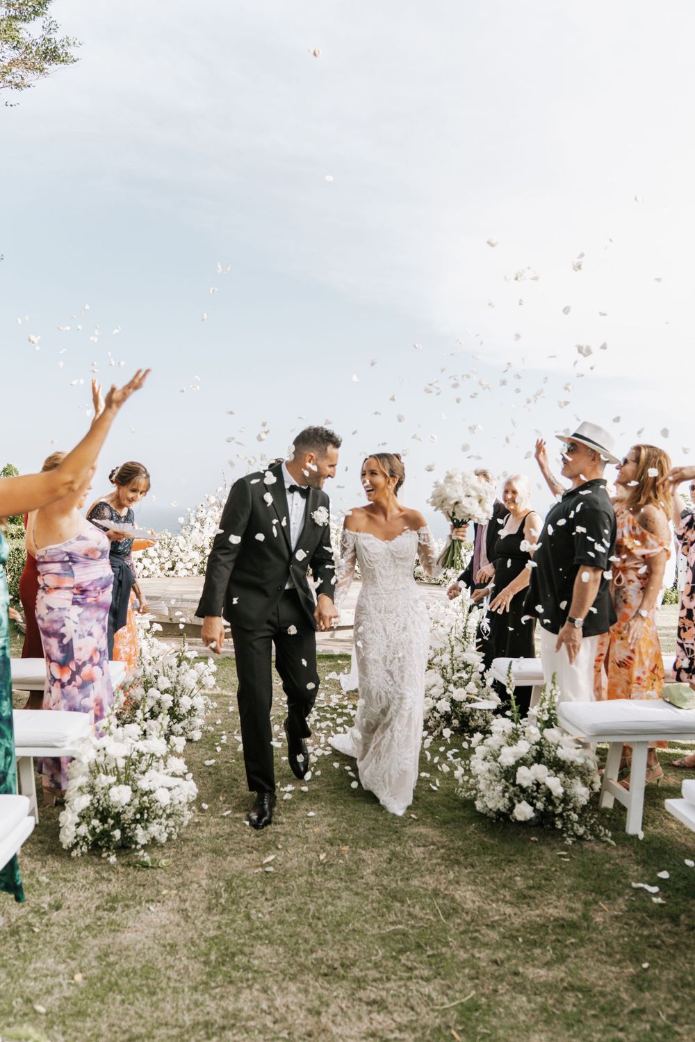 A wedding party celebrates together outside as confetti fills the air during a joyful outdoor ceremony.