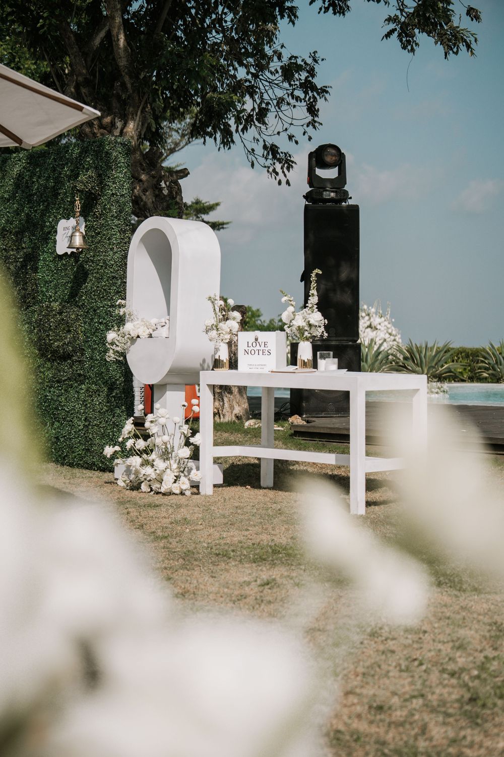 A line of white mailboxes decorated with floral arrangements in an outdoor garden setting.