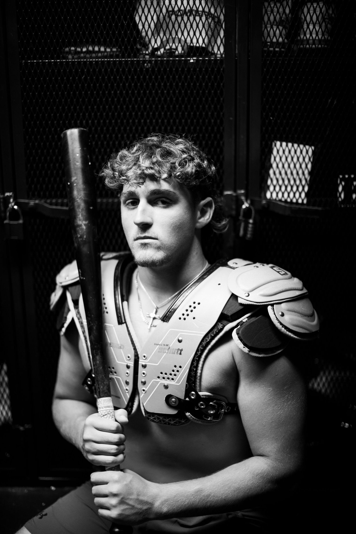 Athletic player wearing protective shoulder and chest gear shown in dramatic black and white lighting.