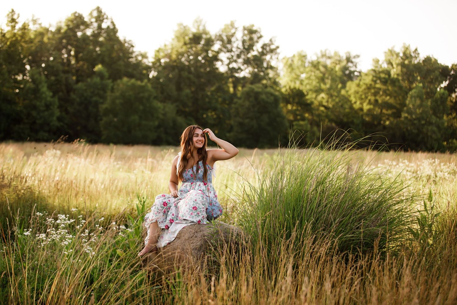 A dreamy golden hour photography session in a field of tall grass and wildflowers during sunset.