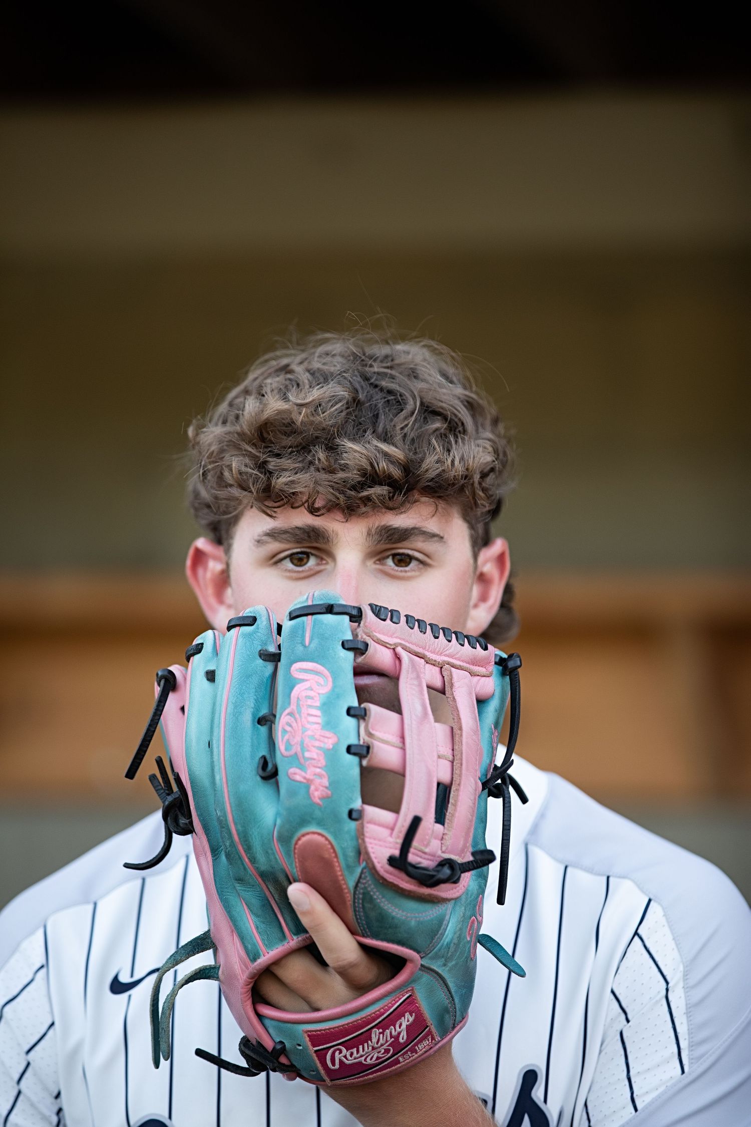 Baseball player in pinstripe uniform adjusts turquoise and pink glove in sequence of four similar photos.