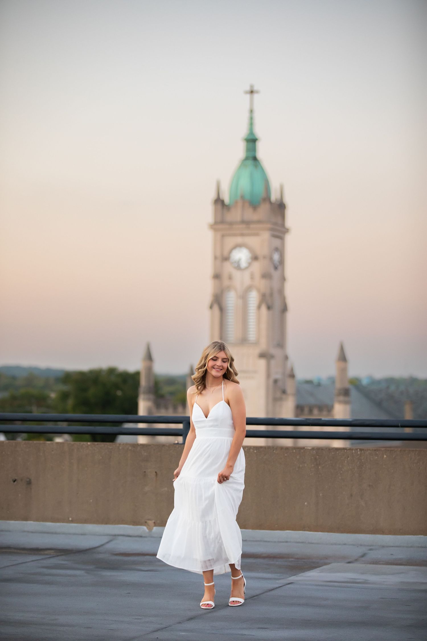 A white dress against church steeples and towers at sunset on a rooftop terrace.