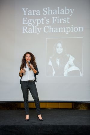 Presenter speaking on stage with presentation slide about Egypt's rally champion.