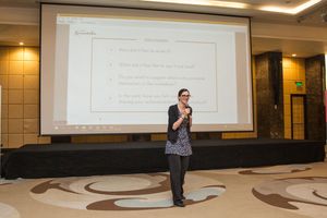 Business presenter speaking in front of projection screen in conference room.