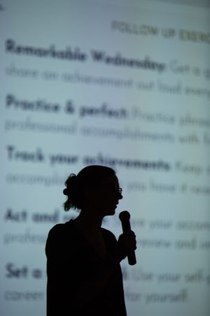 Silhouette figures in front of projection screen showing presentation text.