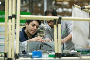 Manufacturing facility worker assembling components at workstation.